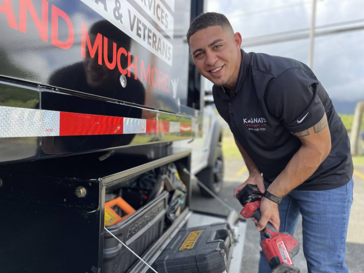 Kana'i putting away tools in one of his branded fleet dump trucks.