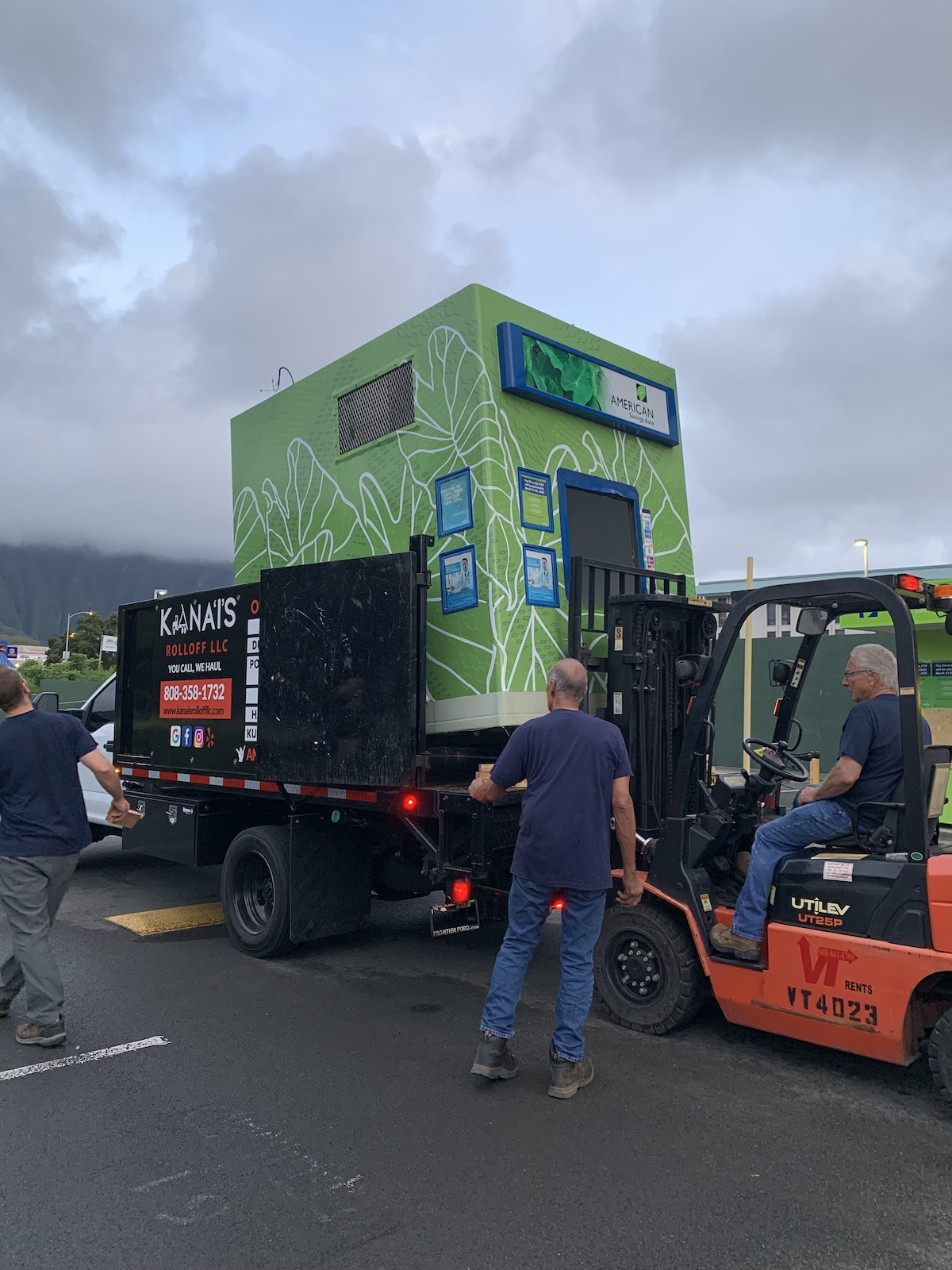 Kana'i's Junk Removal team hauling a green full-sized kiosk in a local parking lot.