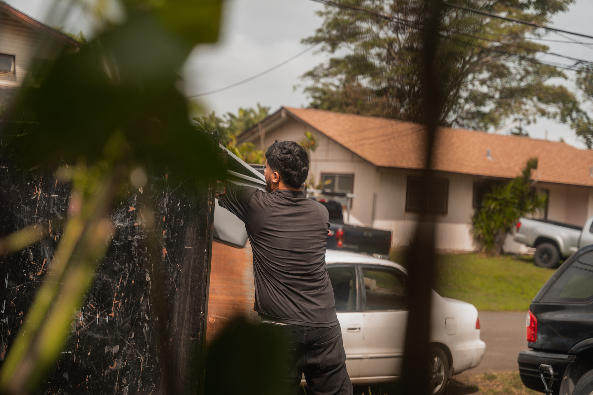 Our Oahu junk removal specialist is throwing away debris from a customers home into a dumpster.