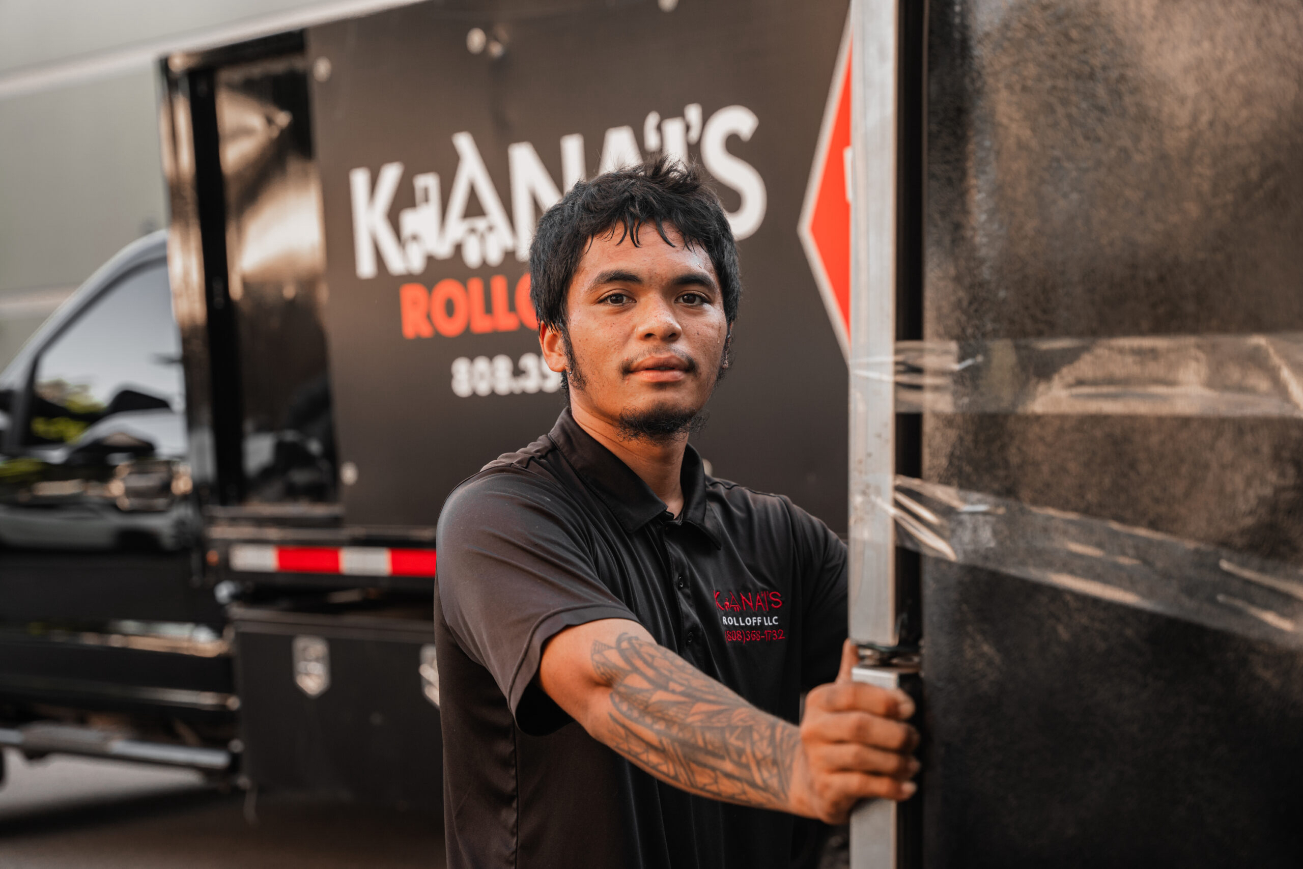 A junk removal worker holding onto our Kana'i's Junk Removal Truck parked outside in Waipio, Oahu.